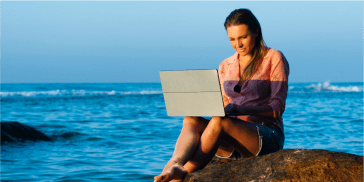 Female traveller on a laptop by the sea