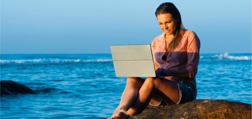 Female traveller on a laptop by the sea